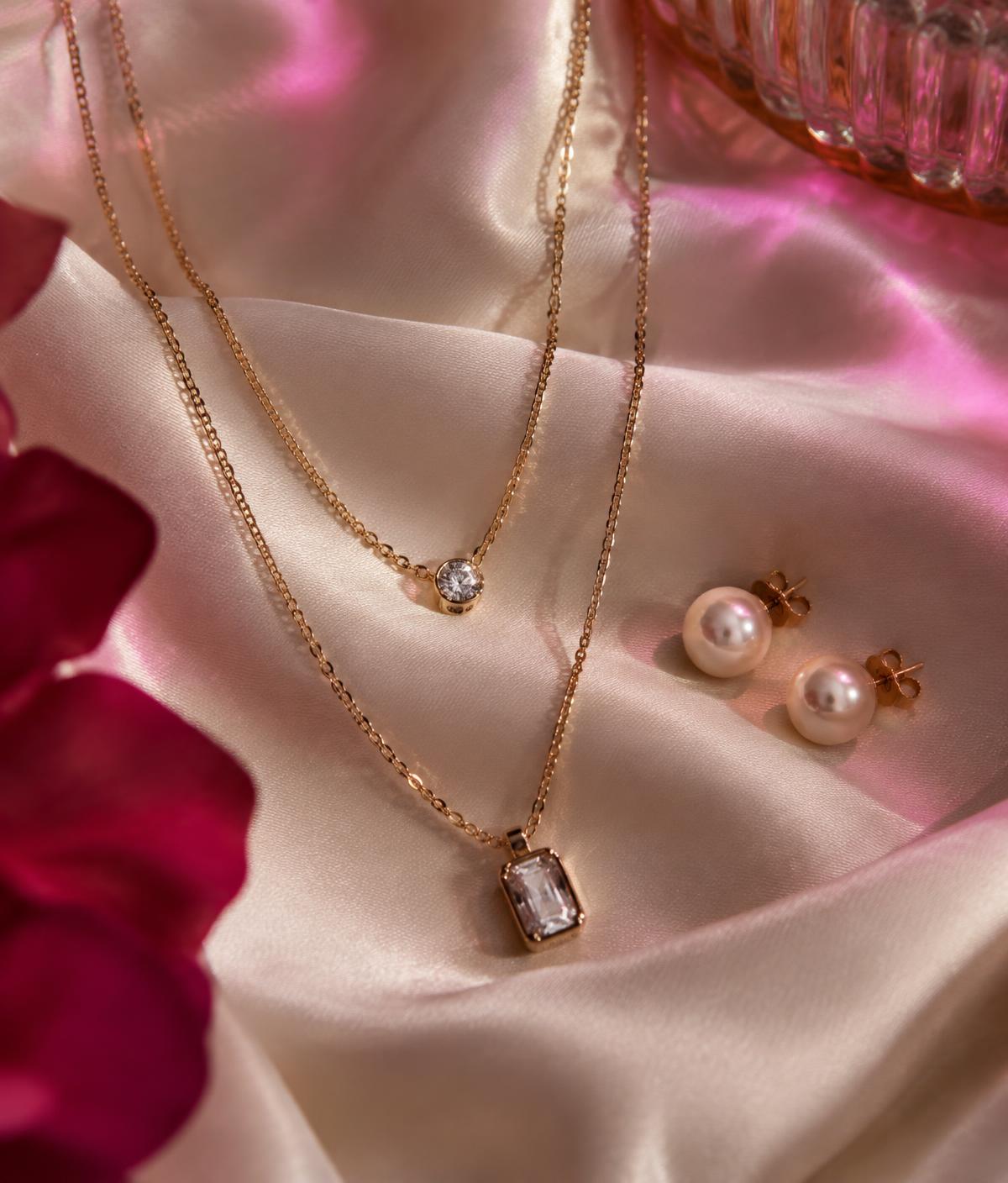 Layered gold necklaces and pearl earrings on ivory silk